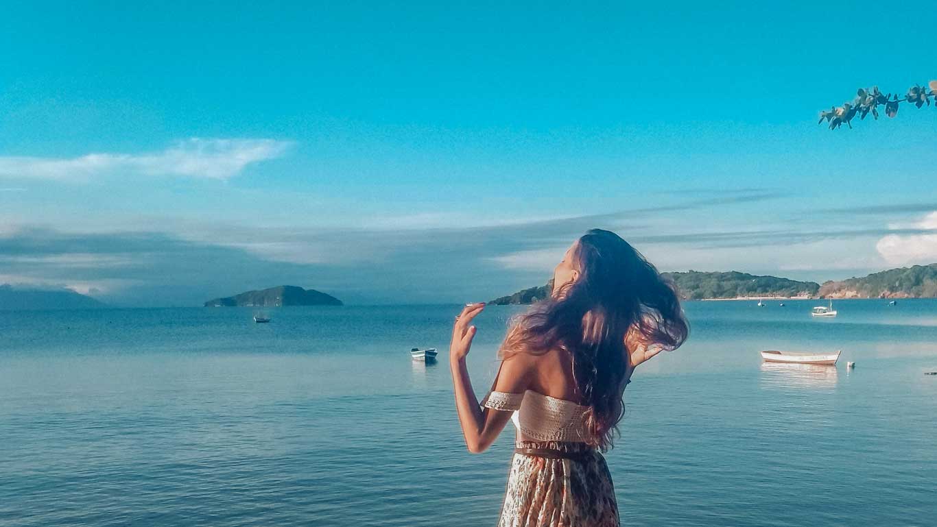 Mujer con el cabello al viento, en Manguinhos, admirando el mar de Búzios.