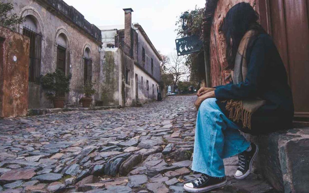 Mujer sentada admirando la hermosa y histórica calle de los Suspiros en Colonia del Sacramento.