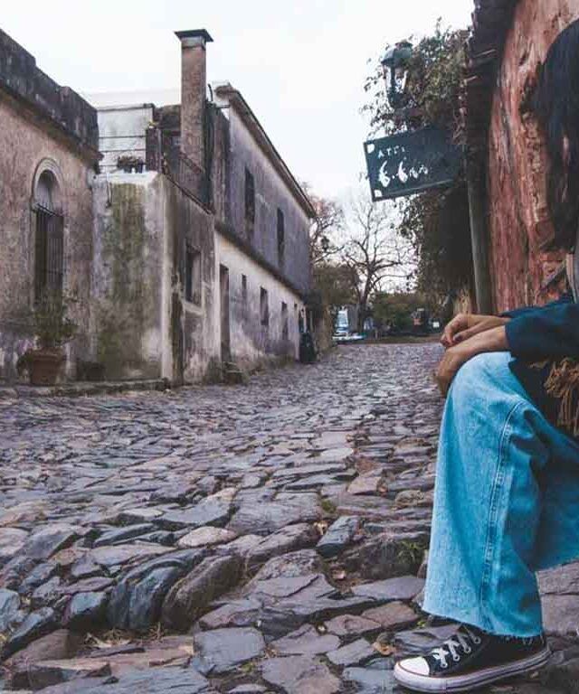 Mujer sentada admirando la hermosa y histórica calle de los Suspiros en Colonia del Sacramento.
