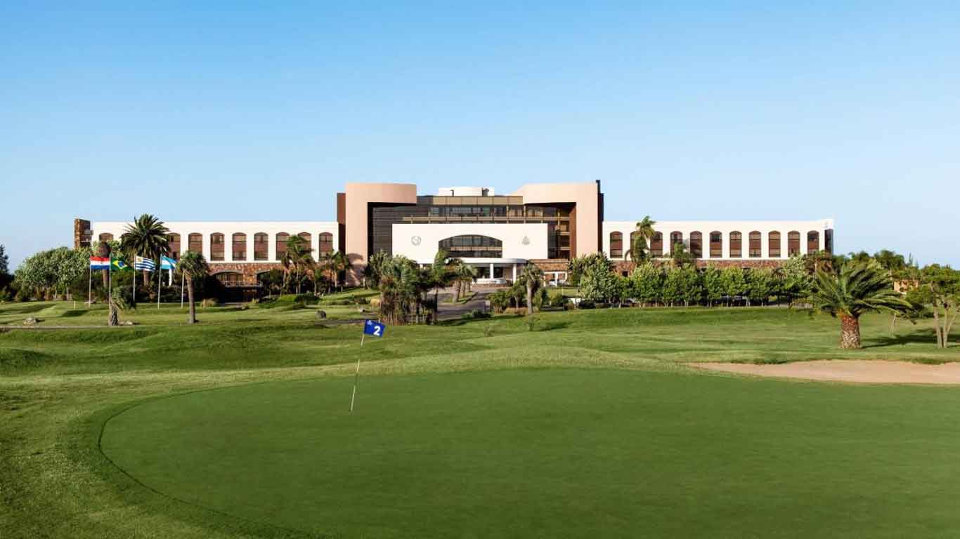 Una amplia vista del Sheraton Colonia Golf & Spa Resort, que muestra la grandeza del edificio con sus numerosas ventanas y terrazas, ubicado en medio de un exuberante campo de golf.