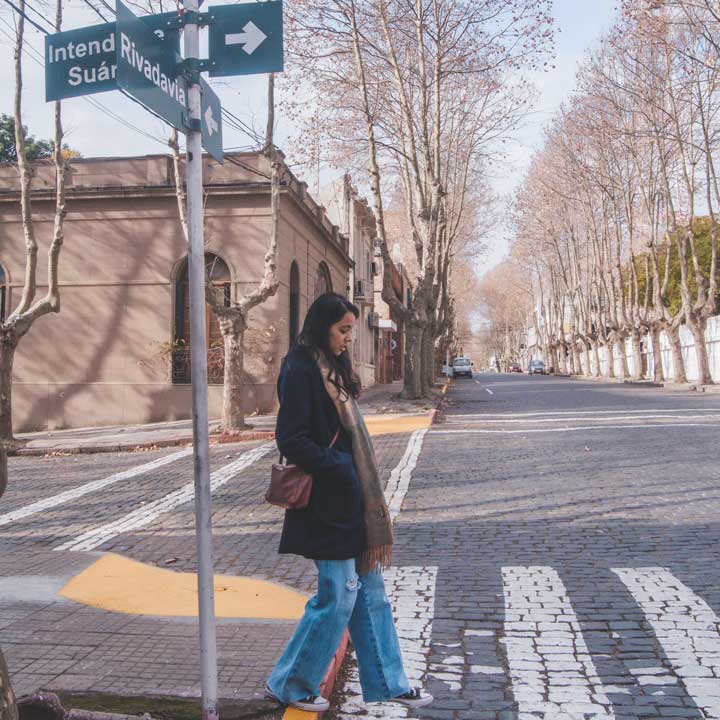 Mujer caminando por el Casco Histórico de Colonia del Sacramento en un día frío y soleado.
