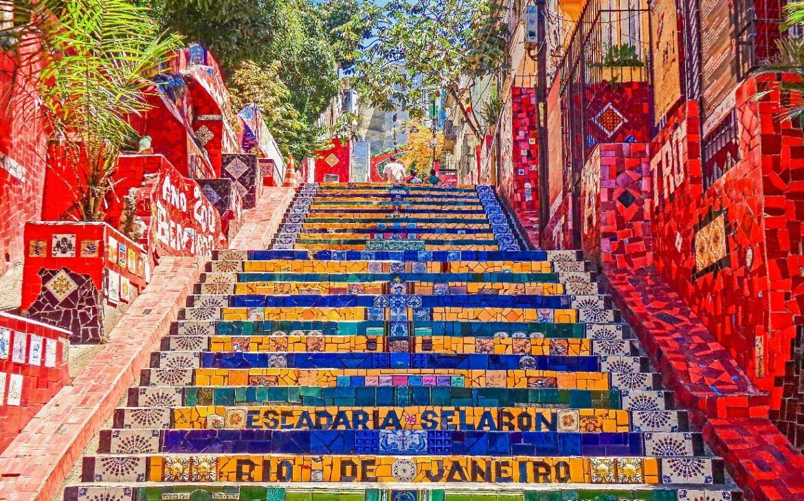 Las vivaces Escaleras de Selarón, un famoso conjunto de escalones en Santa Teresa, Río de Janeiro, decoradas con azulejos de mosaico en colores vibrantes azules, amarillos y rojos e inscripciones, reflejando el estilo artístico y la riqueza cultural del área.