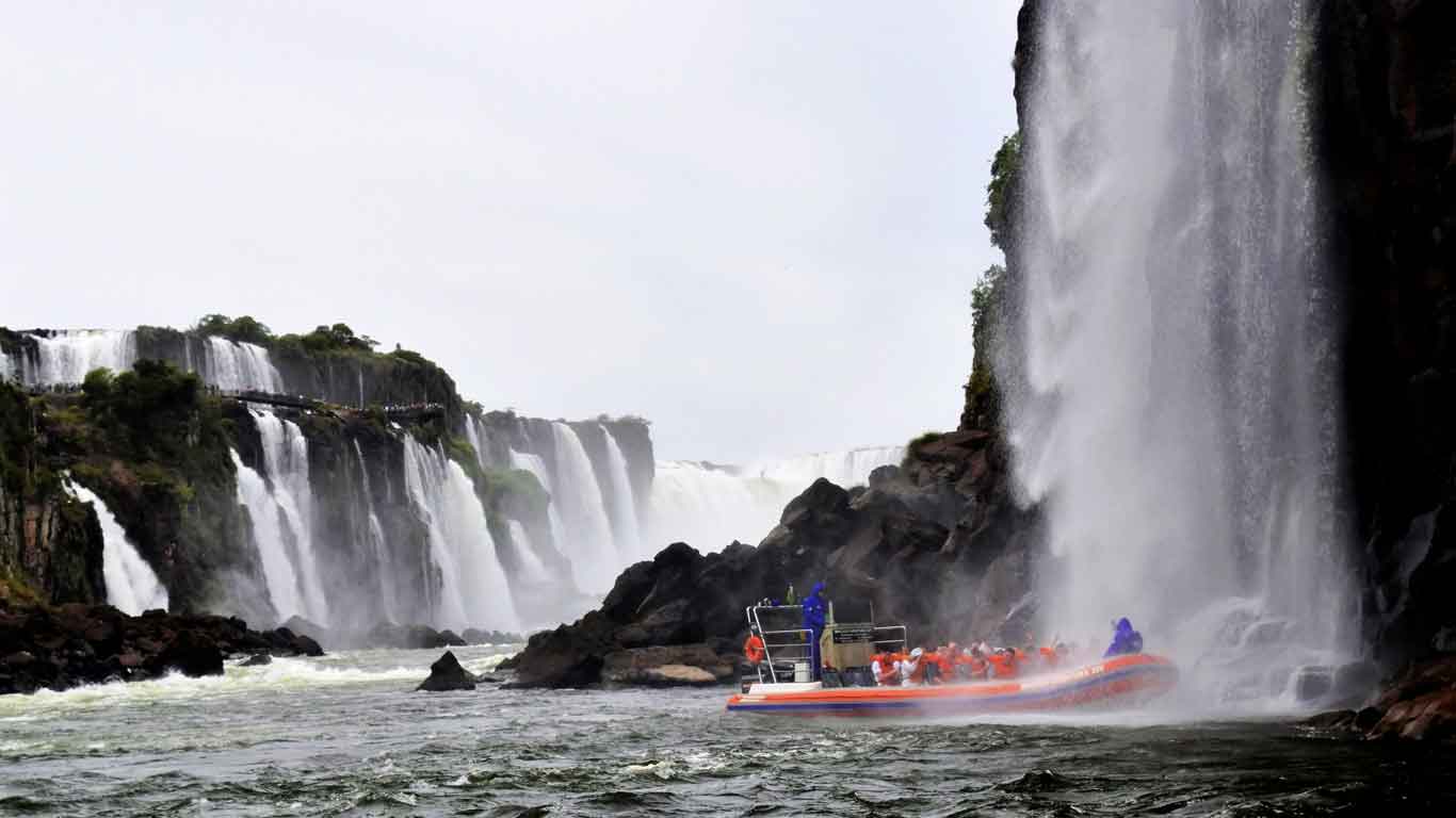 Barco parado debajo de las cascadas de agua de las Cataratas del Iguazú, en el paseo en lancha.