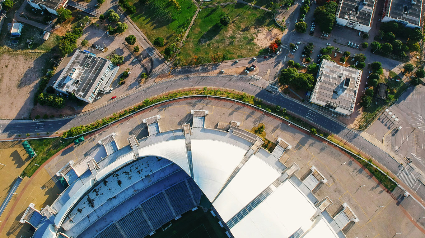 arena-das-dunas-natal Fotografía aérea del estadio Arena das Dunas en Natal, rodeado de calles y edificios, destacando por su arquitectura moderna y ubicación estratégica. Ideal para quienes buscan donde alojarse en Natal cerca de eventos deportivos y grandes espectáculos.