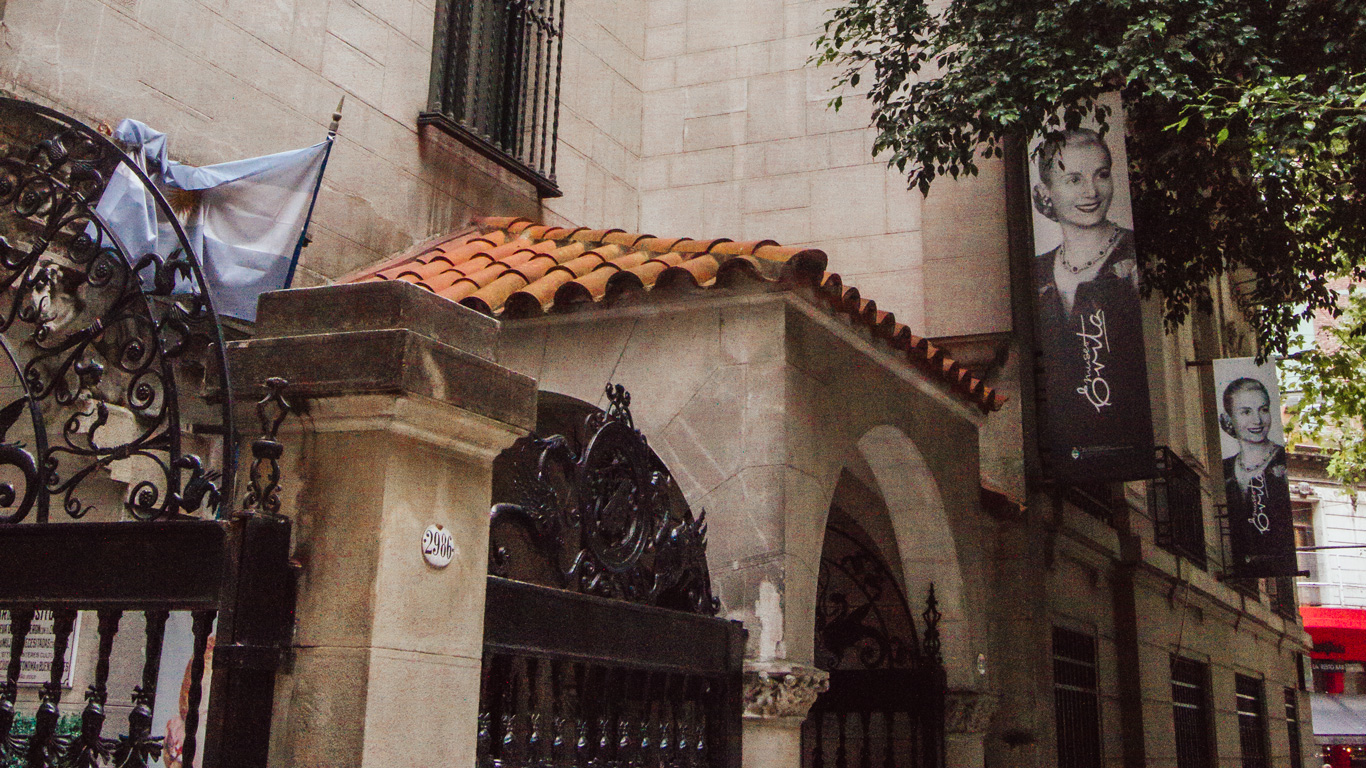museu-evita-palermo Entrada del Museo Evita en Palermo, Buenos Aires, con su arquitectura tradicional y portones ornamentados. Banderolas con la imagen icónica de Eva Perón decoran la fachada.