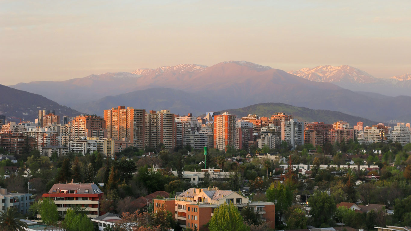 vista-a-las-cordilleras-de-los-andes-de-santiago Vista de la ciudad de Santiago al atardecer con la Cordillera de los Andes al fondo, mostrando cumbres con nieve tenue.