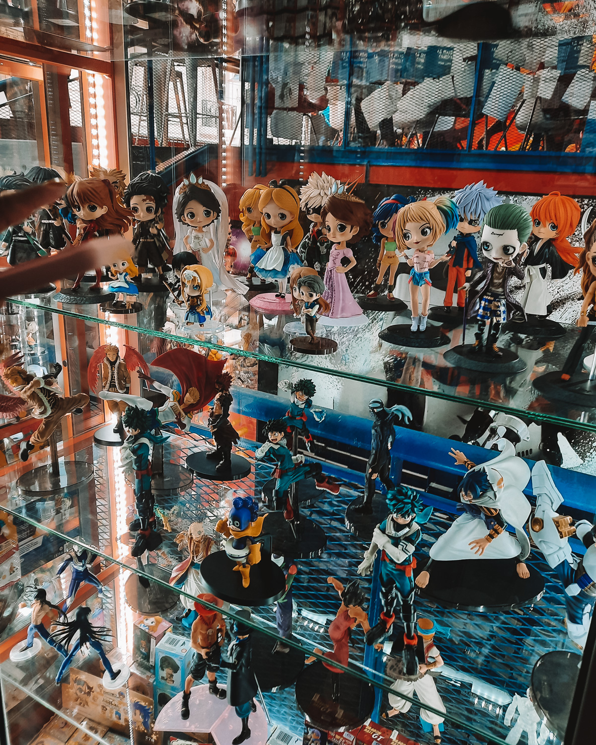 La-Revisteria-Buenos-Aires Una vitrina de La Revistería – Comics & Coffee está repleta de miniaturas de personajes de anime y dibujos animados, organizadas en filas iluminadas.