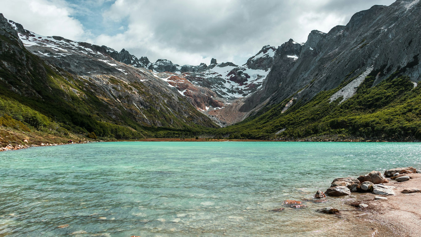 Aguas verde esmeralda de la Laguna Esmeralda rodeadas de montañas nevadas y vegetación densa en los alrededores de Ushuaia.