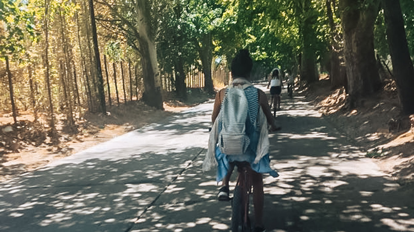 Mujer paseando en bicicleta por una calle arbolada durante el recorrido wine bike tour en Mendoza.