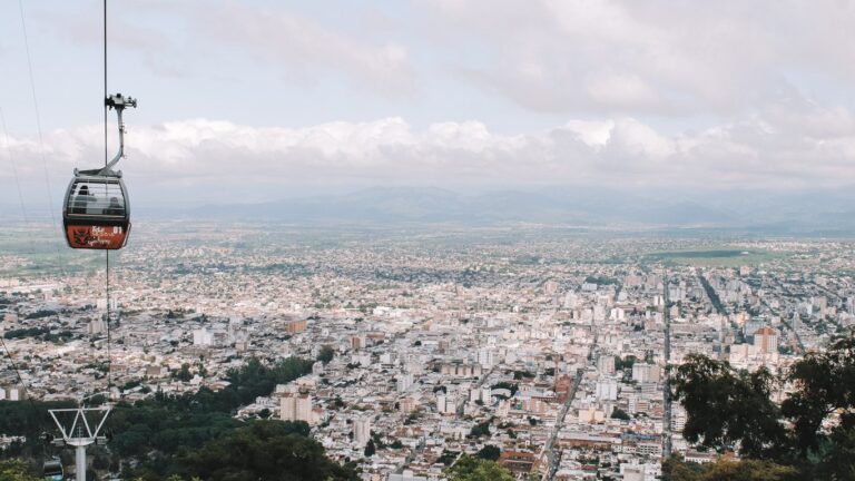 Salta vista desde un mirador con un teleférico en primer plano. La ciudad se mezcla con el cielo ligeramente nublado en el horizonte.